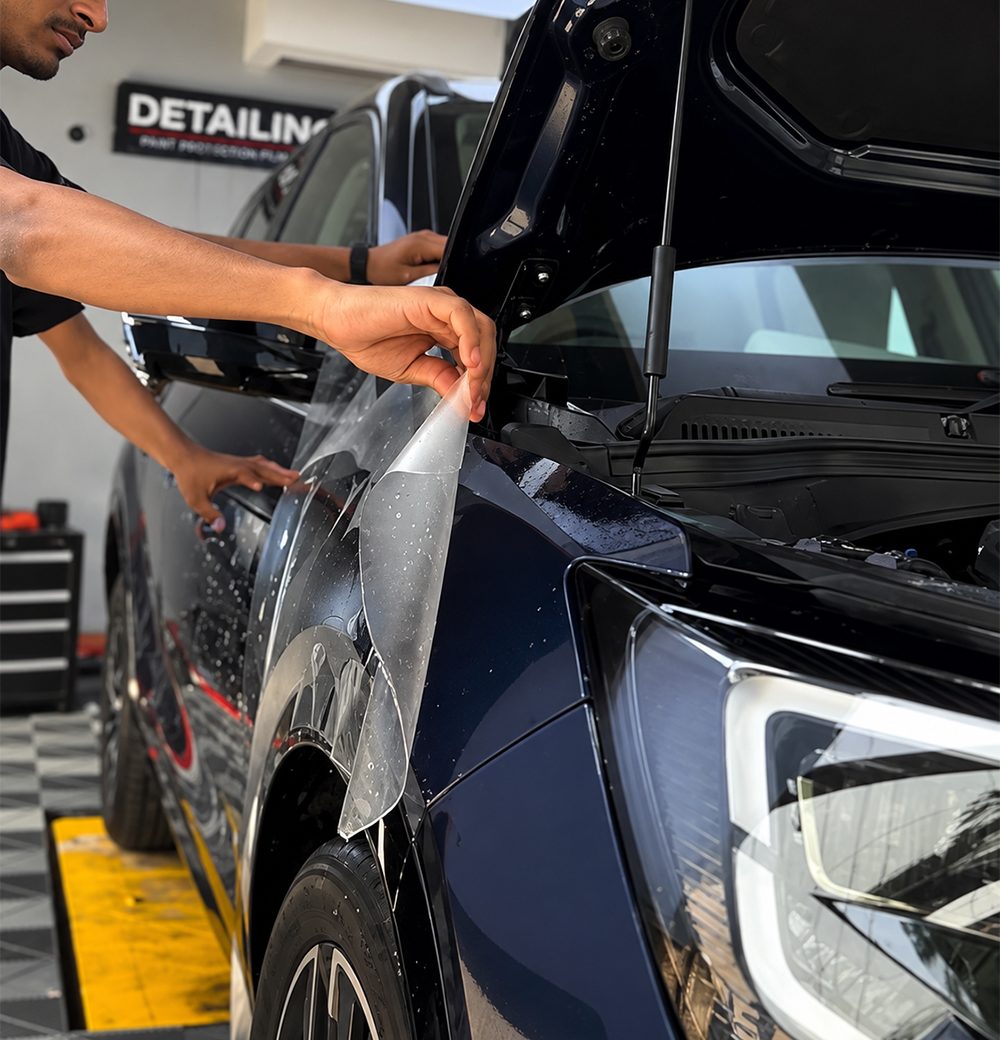 Technician applying paint protection film to a car&rsquo;s front fender
